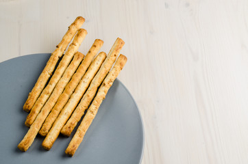 rustic breadsticks in a dish on wood table, close up, background