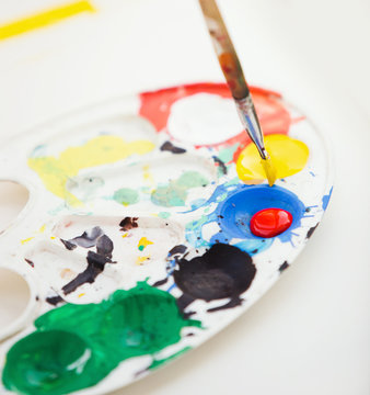 Plastic paint palette with paint and brush, close up photo