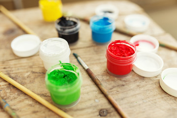 Brushes with colorful paints on old wooden background