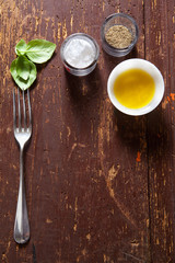 the concept of food on old wooden board. fork, olive oil, basil