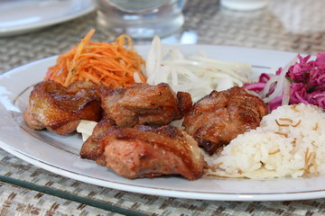Grilled meat.
Fresh portion of shish kebab on plate with onion and greens.