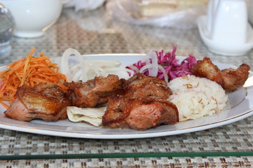 Grilled meat.
Fresh portion of shish kebab on plate with onion and greens.