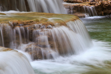 Fototapeta premium Water flowing over rocks in waterfall cascade in a forest