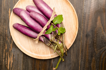 Fresh eggplants on wooden plate