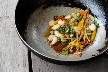 Shell fried clams in pan on wood  background