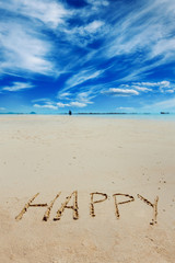Sign of happy caption written on golden sand at blue summer sky