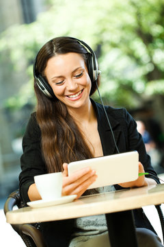 Young woman using tablet and listening music in cafe