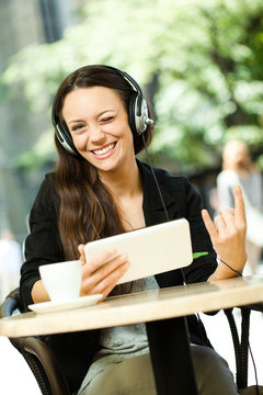 Young woman using tablet and listening music in cafe