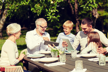 happy family with tablet pc at table in garden