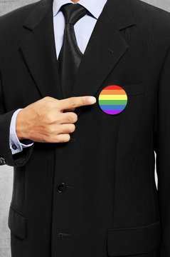 Business man show his gay flag pin