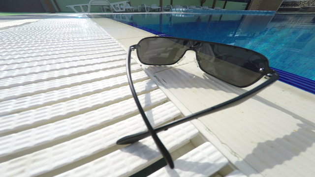 Sunglasses at the edge of hotel swimming pool outdoor