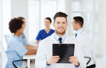 happy doctor with tablet pc over team at clinic