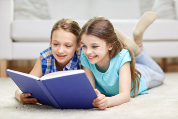 two happy girls reading book at home