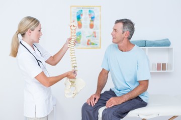 Obraz premium Doctor showing anatomical spine to her patient 