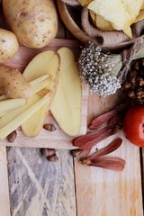 Potato chip and fresh potatoes on wood background