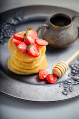 Stack of sweet pancakes with strawberry and honey.