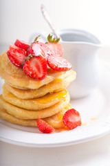 Stack of sweet pancakes with strawberry and honey.