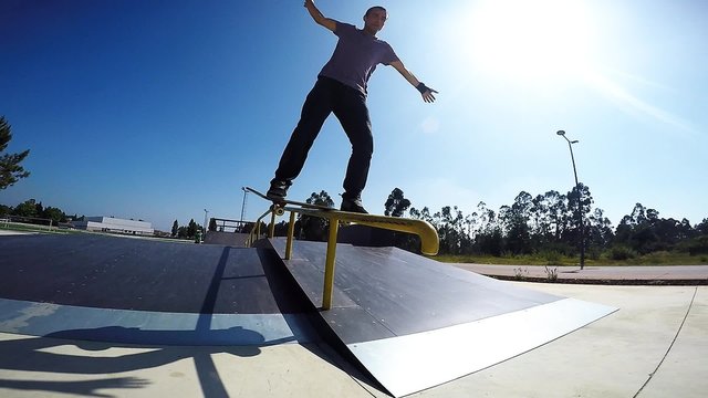 Slow motion extreme skateboarder sliding down rail