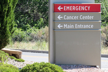 Sign at a hospital with directions to the emergency room, cancer center and main entrance