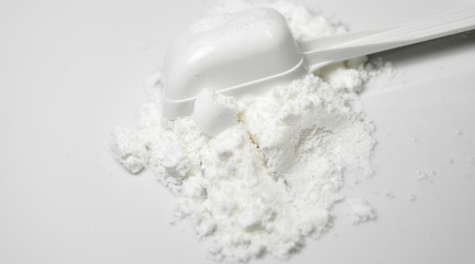 Scoop of White Collagen amino protein powder  poured with spoon