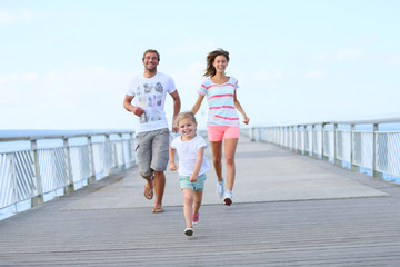 Little girl with parents running on a bridge