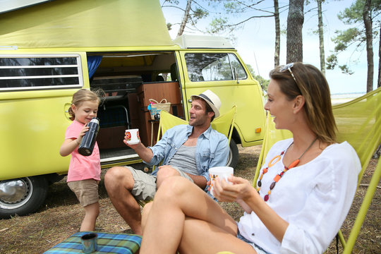 happy family relaxing by camper van in summer