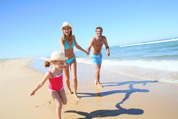 Family having fun running on a sandy beach