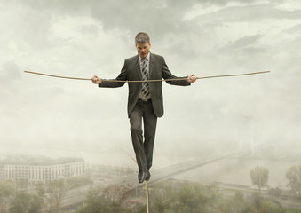 Businessman Walking on a Rope Keeping Balance with City Under-Venture Business Concept