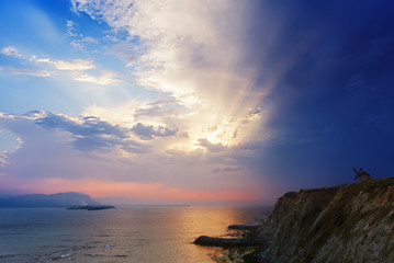 Aixerrota mill with sun rays and stormy clouds