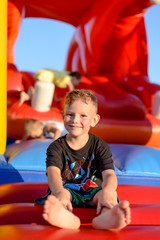 Smiling little boy sitting on a jumping castle