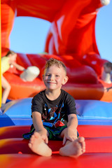 Fototapeta na wymiar Smiling little boy sitting on a jumping castle