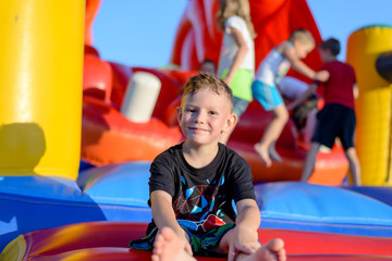 Fototapeta na wymiar Smiling little boy sitting on a jumping castle