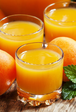 Fresh apricot juice and apricots with mint on old wooden table,