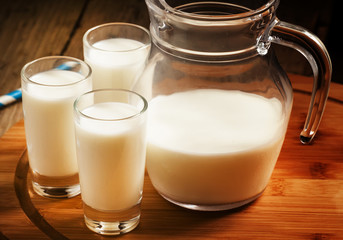 Fresh peasant milk jug and glasses on  wooden table, selective f