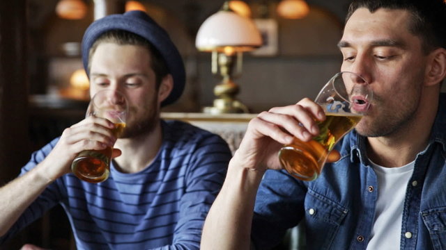 happy male friends drinking beer at bar or pub