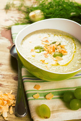 Cold green gaspacho soup with grapes, almonds and dill on grunge wooden rustic background. Selective focus