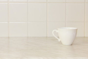 Ceramic tea cup on white kitchen table.