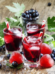 Red cold cocktail with berries currants and red heart-shaped ice