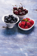 Sweet organic berries: raspberry, blueberry and cherry in white bowls. Selective focus