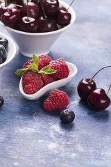 Sweet organic berries: raspberry, blueberry and cherry in white bowls. Selective focus