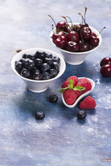 Sweet organic berries: raspberry, blueberry and cherry in white bowls. Selective focus