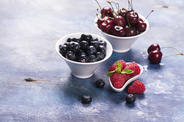 Sweet organic berries: raspberry, blueberry and cherry in white bowls. Selective focus