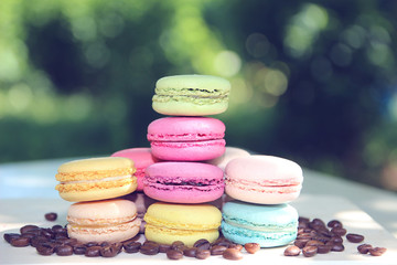 Fototapeta na wymiar Colorful french macaroons with coffee on the nature background