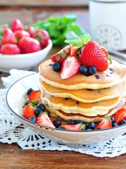 Blueberry Pancake with strawberries and a cup of milk on a wooden table