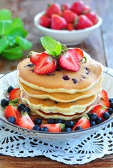 Blueberry Pancake with strawberries and a cup of milk on a wooden table