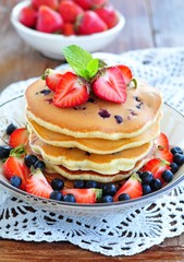 Blueberry Pancake with strawberries and a cup of milk on a wooden table
