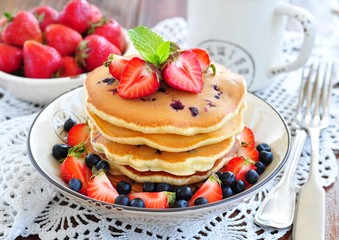 Blueberry Pancake with strawberries and a cup of milk on a wooden table