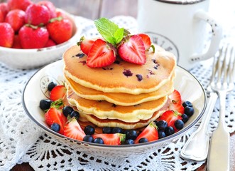 Blueberry Pancake with strawberries and a cup of milk on a wooden table