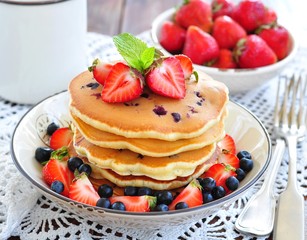 Blueberry Pancake with strawberries and a cup of milk on a wooden table