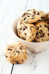 Chocolate chip cookies in bowl on white wooden background